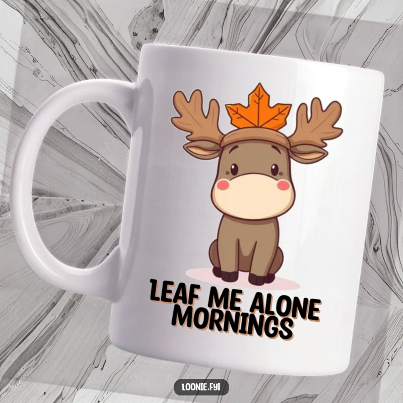 Funny Moose Mug showing a confused moose attempting to wear a large maple leaf as a fashionable hat, looking bewildered.