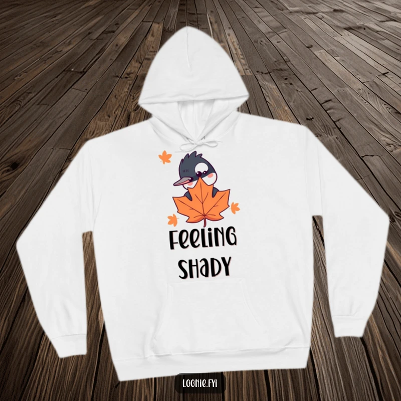 Funny hoodie with a curious loon hiding behind a stylized maple leaf, bringing cozy humor to your outdoor adventures.