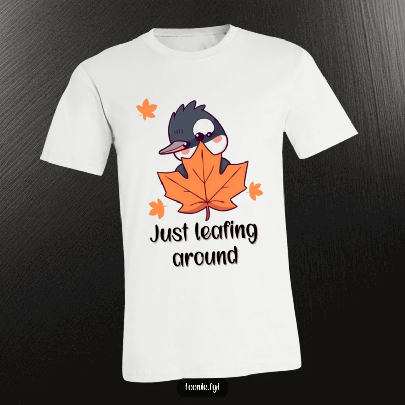 Funny T-shirt showcasing a curious loon peeking from behind a maple leaf, offering a delightful and humorous woodland scene.